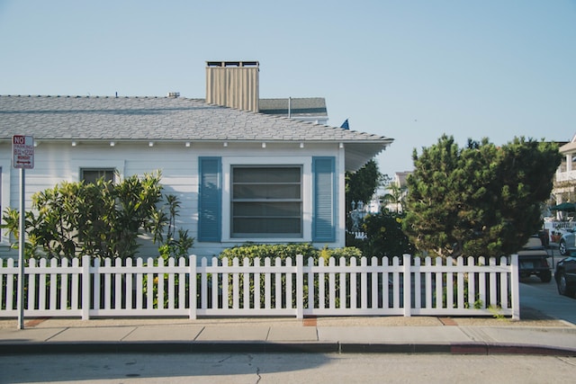 Blue bungalow with a white picket fence and blue shutters